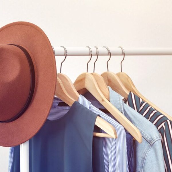 collection-clothes-with-brown-hat-hanging-rack-near-white-wall-clothes-women-blue-colors-office-style_131761-7